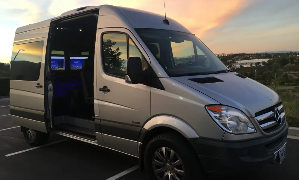 The PM Appraisal mobile appraisal vehicle, a silver van with its side door open showing two monitors inside